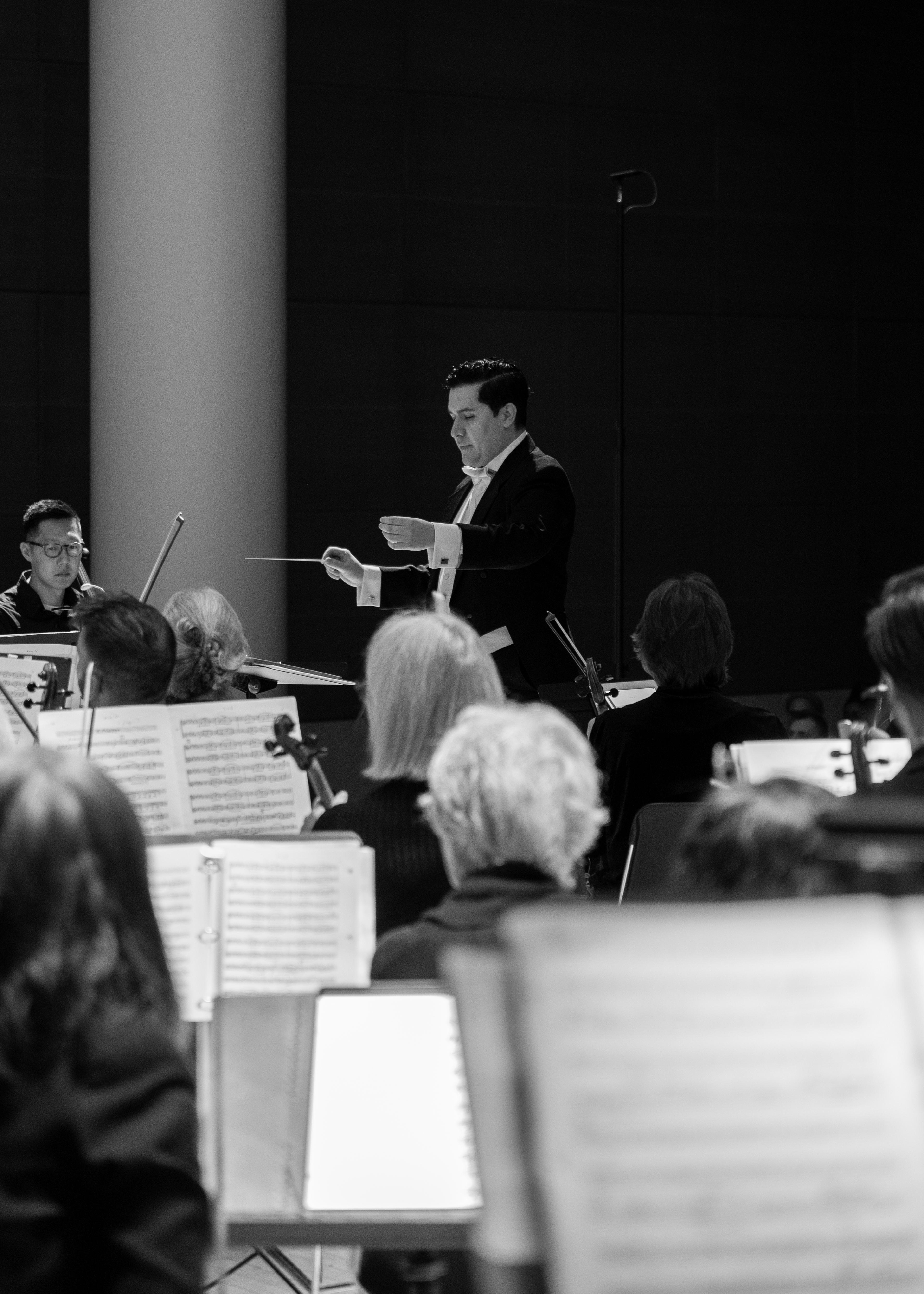 Black-and-white photograph of a conductor leading an orchestra