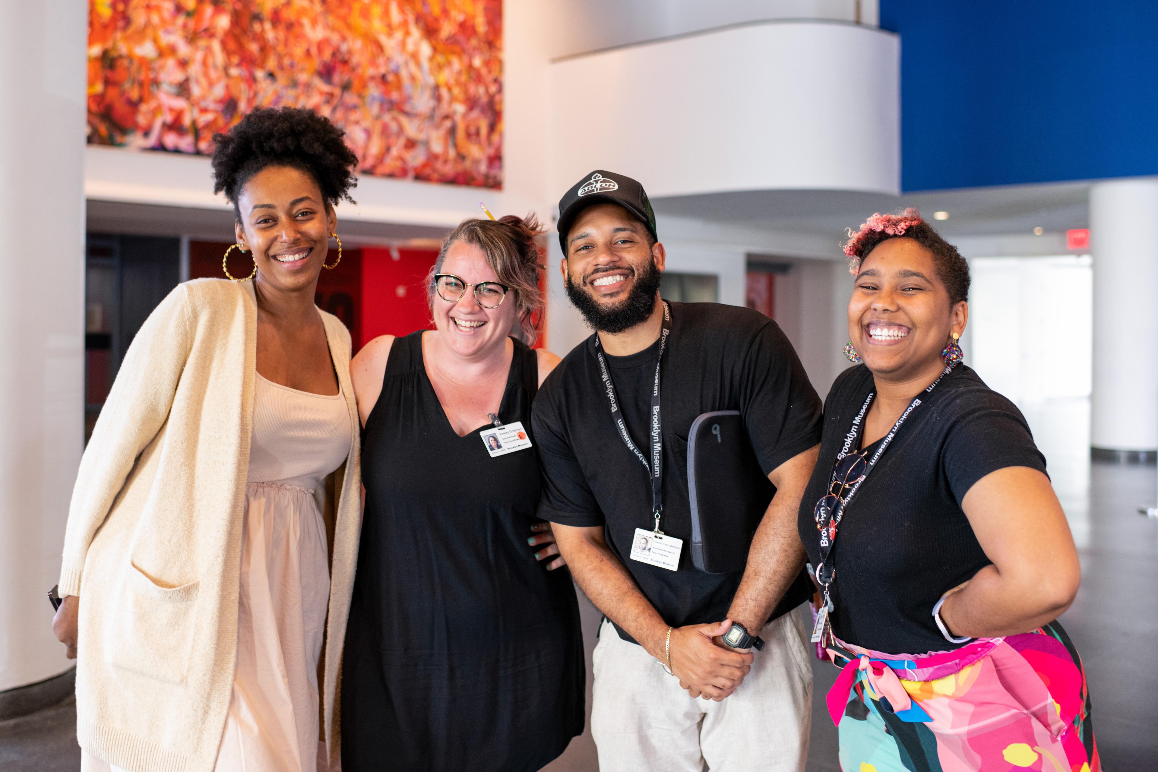 Four adults smile for a picture in the Brooklyn Museum lobby