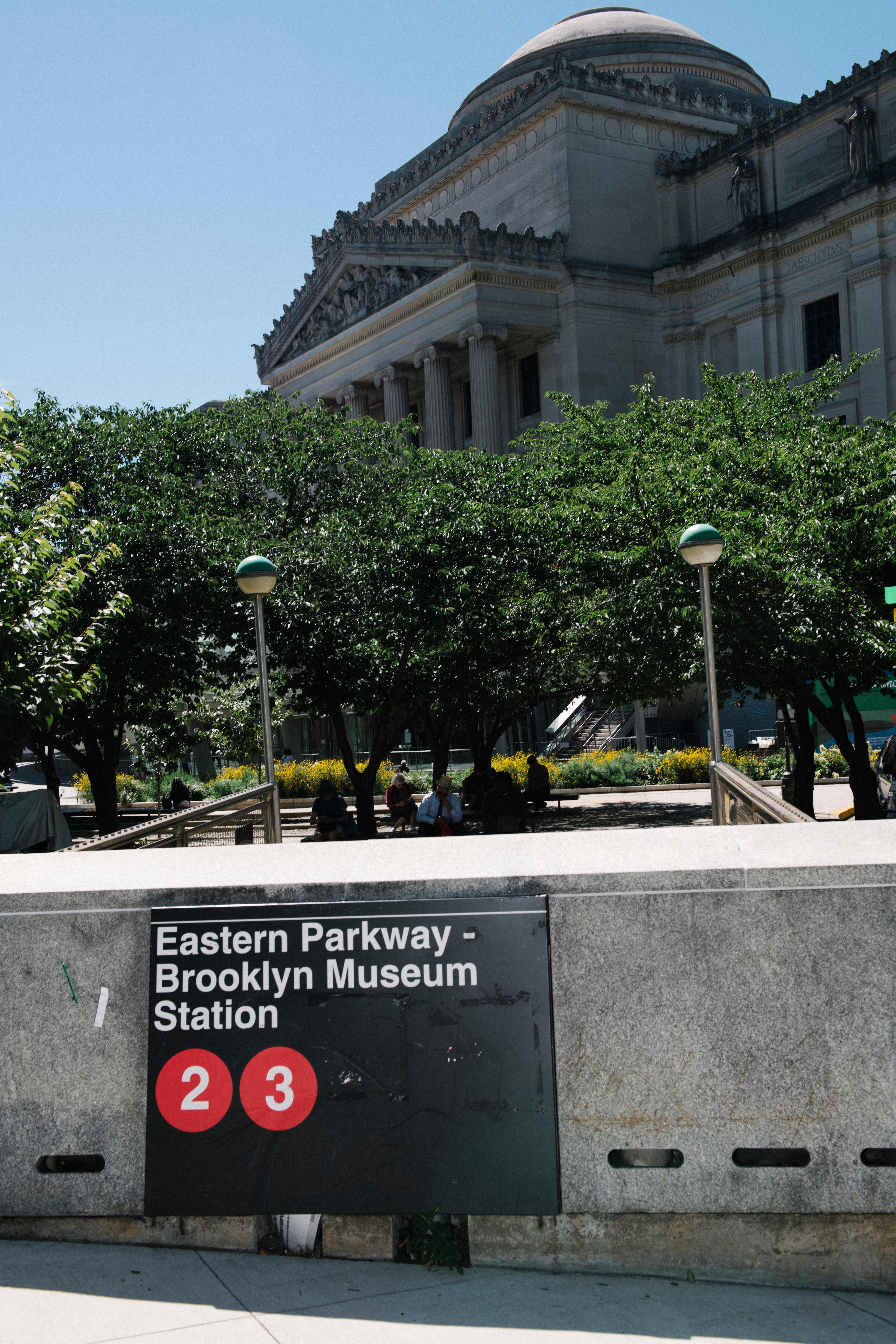 Subway entrance that reads "Eastern Parkway–Brooklyn Museum 2 3" which a neoclassical building in the background