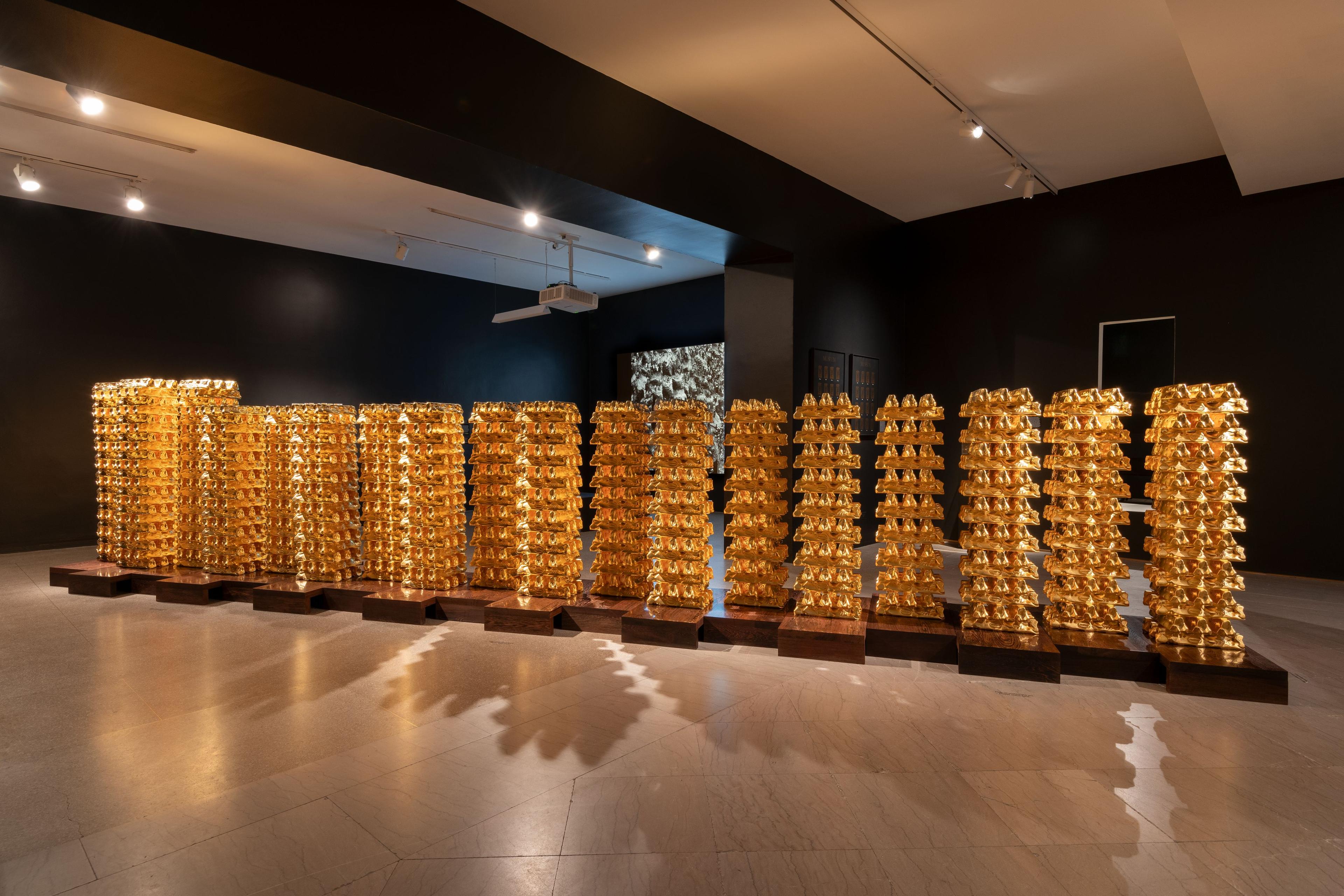 An artwork comprising many stacks of gold bars