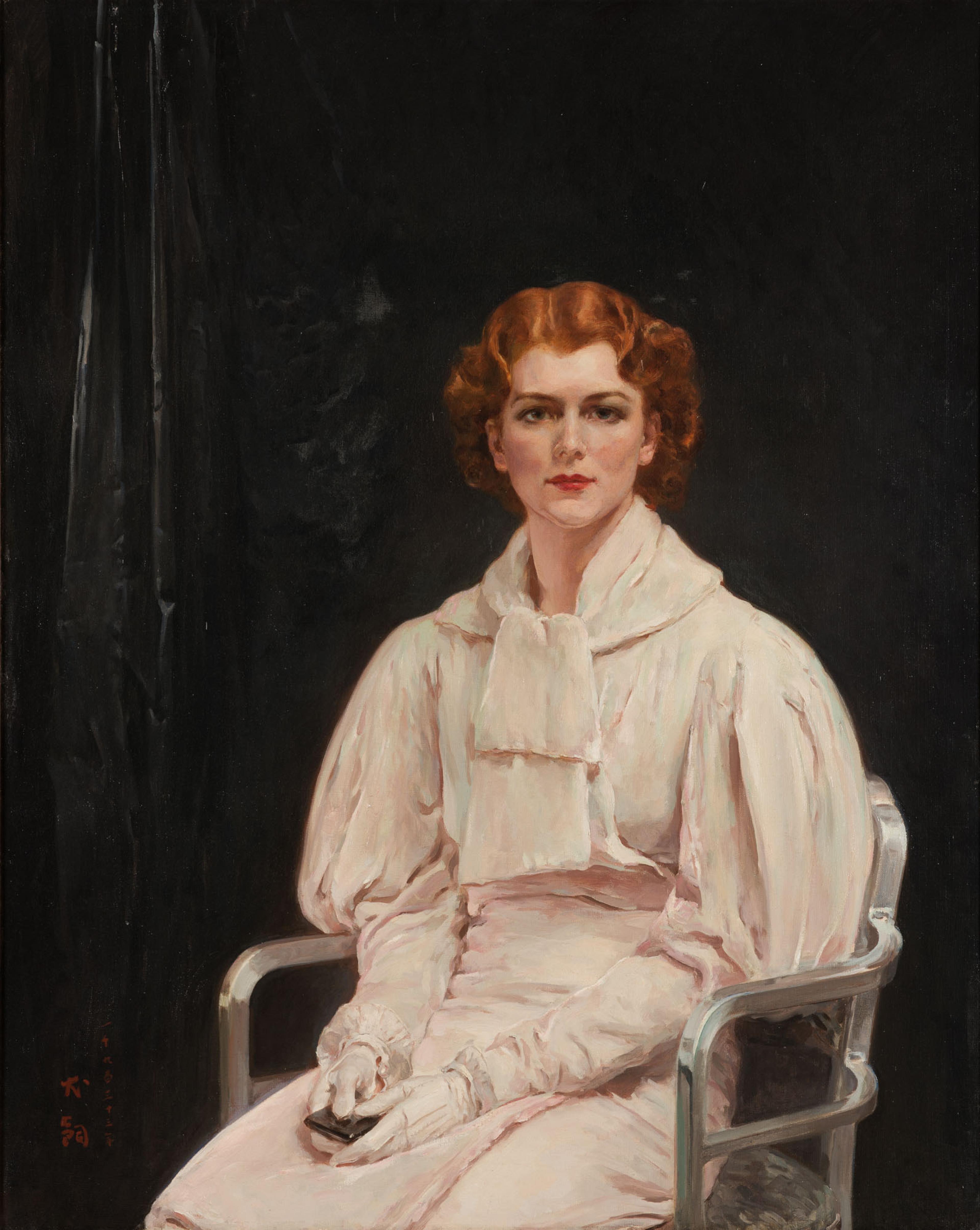 Red headed person dressed in a pale pink dress sits in a silver chair against a black background