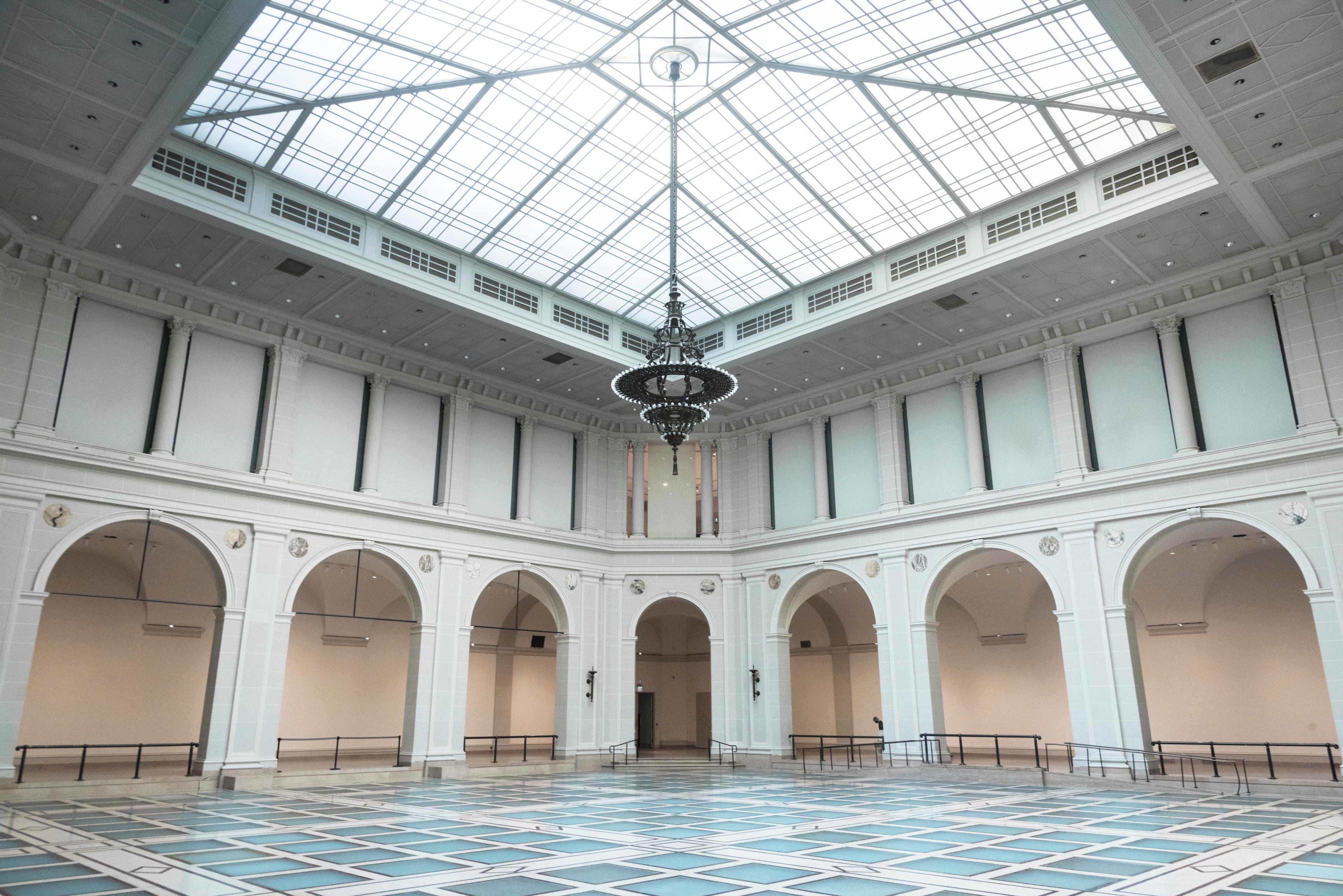 Light-filled, 2-story atrium with large chandelier and glass floor surrounded by arches